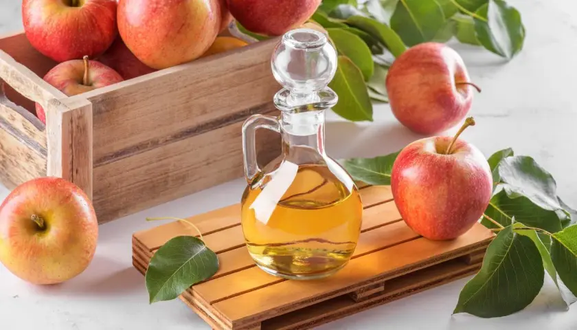 Bouteille de vinaigre de cidre et pommes fraîches, évoquant les bienfaits naturels pour la prostate.