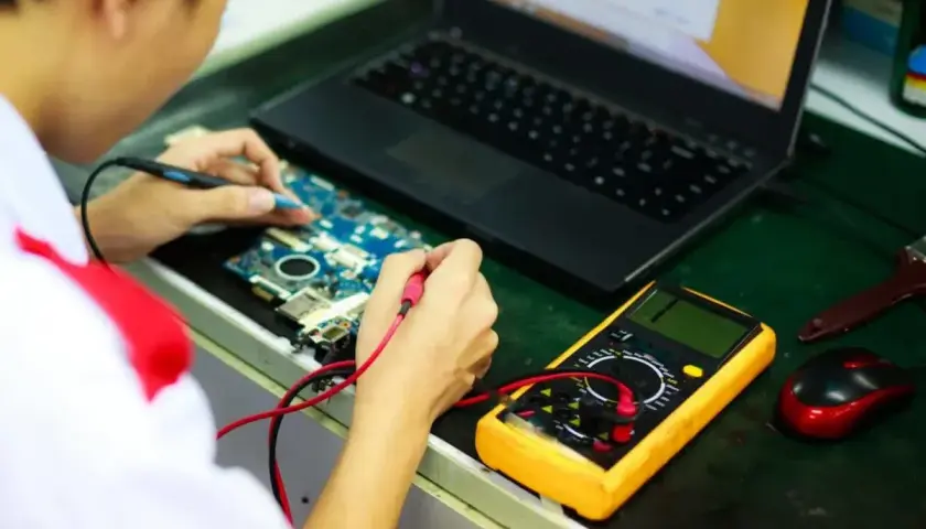 Inżynier elektroniki bada płytę główną z multimetrem. Zastanawiasz się, ile zarabia inżynier elektroniki?
