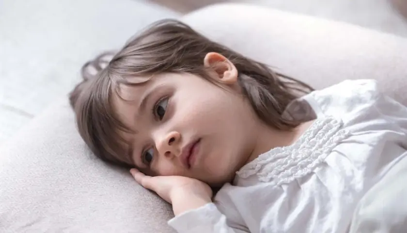 Smutna dziewczynka, 1,5 roczne dziecko, leży na poduszce, nie chce spać, zamyślona.