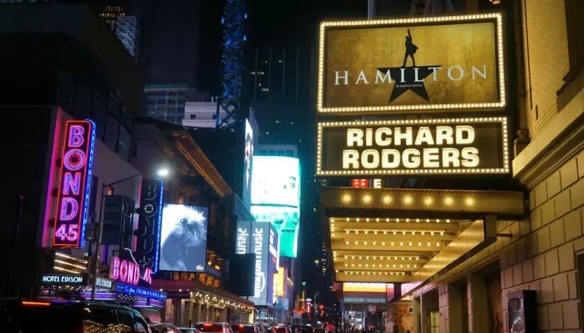 Broadway-skyltar lyser upp natten. Hamilton musikal visas på Richard Rodgers Theatre, omgivet av neonljus och trafik.