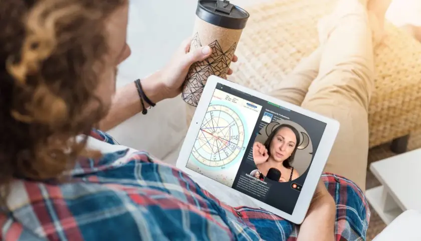 Mężczyzna ogląda na tablecie horoskop, gdzie widoczna jest Wenus w Byku. Kobieta tłumaczy astrologiczne niuanse.
