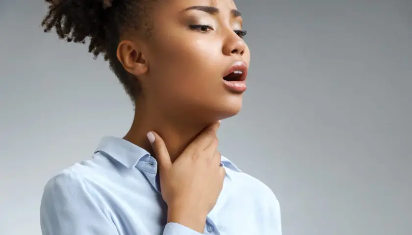 Femme portant la main à sa gorge, bouche ouverte, possiblement atteinte de scarlatine adulte.