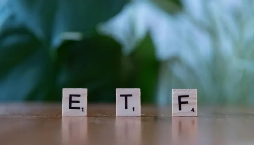 Litery ETF na drewnianych klockach symbolizują inwestycje, które mogą pomóc w nauce, jak zarabiać na giełdzie.