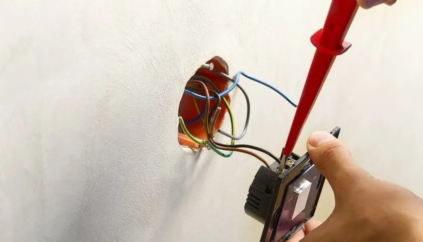 Instalator podłącza podwójny włącznik, pokazując, jak podłączyć dwie lampy do podwójnego włącznika.