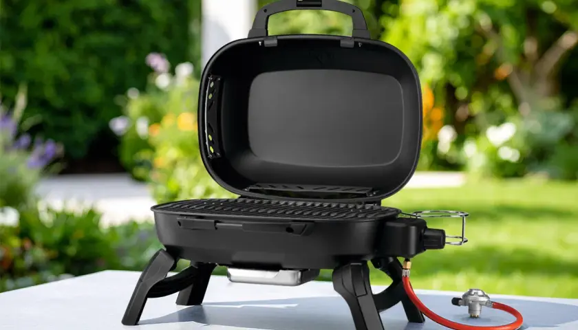 Barbecue à gaz portable, ouvert, avec couvercle, prêt pour de délicieuses recettes barbecue gaz avec couvercle dans un jardin ensoleillé.