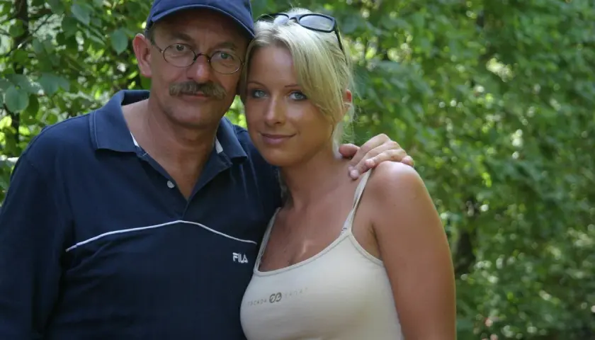 Mężczyzna w okularach i czapce obejmuje kobietę w bluzce na ramiączkach.