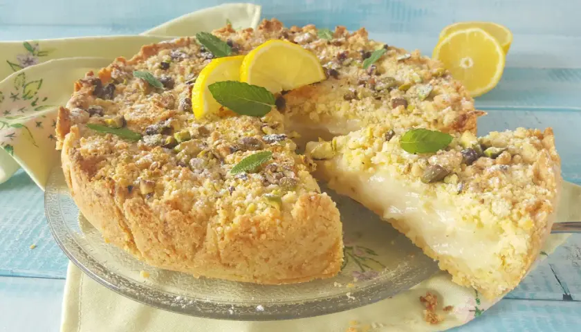 Deliziosa sbriciolata al limone con crema soffice, guarnita con pistacchi, menta e spicchi di limone fresco.
