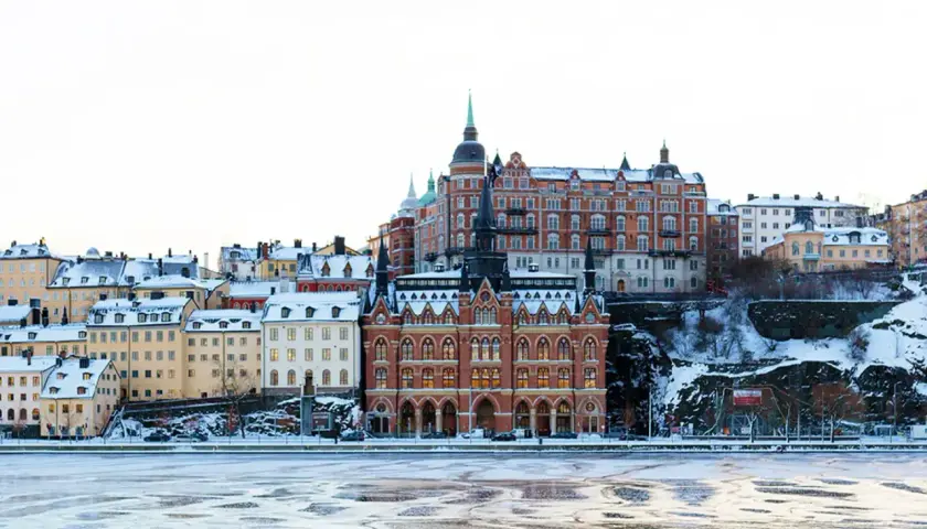 Vinter i Stockholm: snöklädda hus längs vattnet, perfekt för mysiga promenader och fika.