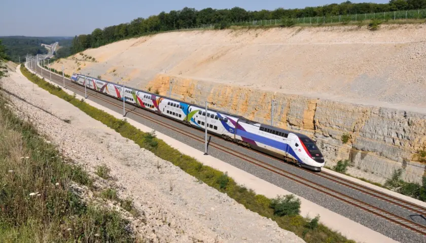 Kolorowy pociąg TGV pędzi po torach, pokazując, jak szybko jedzie pociąg Intercity.