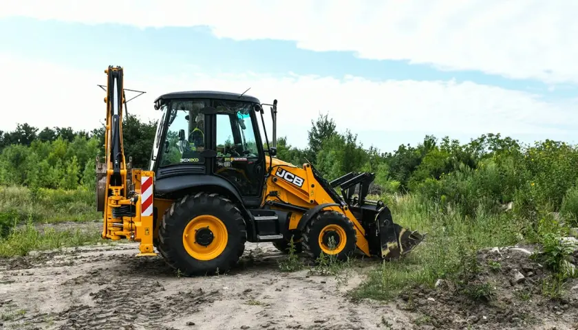 Żółta koparko-ładowarka JCB na placu budowy. Uprawnienia na koparko ładowarkę do czego uprawniają? Do obsługi maszyn budowlanych, takich jak ta.