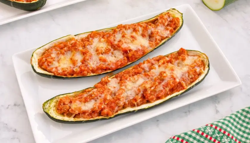 Dos calabacines rellenos de carne y queso gratinado, servidos en un plato blanco.