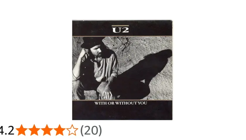 U2 w kadrze z piosenki "With or Without You". Mężczyzna w kapeluszu siedzi na ziemi, rzucając długi cień.