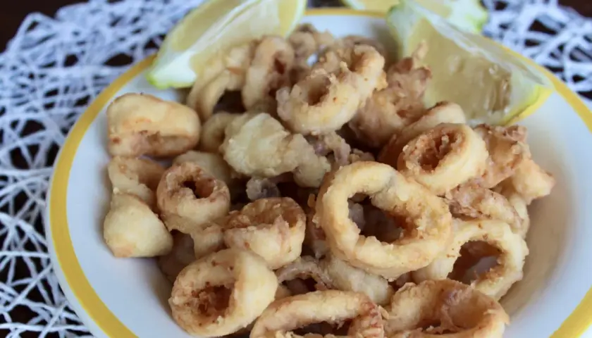 Un piatto invitante di frittura di calamari dorati e croccanti, accompagnati da spicchi di limone fresco.