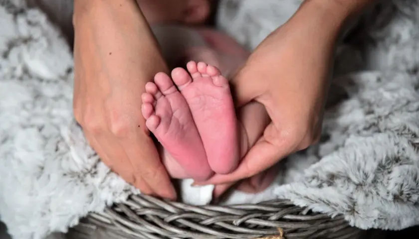 Delikatne stópki niemowlaka otulone dłońmi w koszyku. Piękne zdjęcia niemowlaka, pełne czułości i miłości.