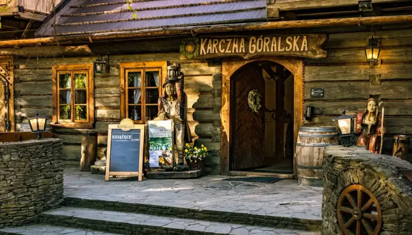 Drewniana karczma góralska, przyciągająca licznymi atrakcjami. Przed wejściem drewniane rzeźby, beczki i kamienne murki.