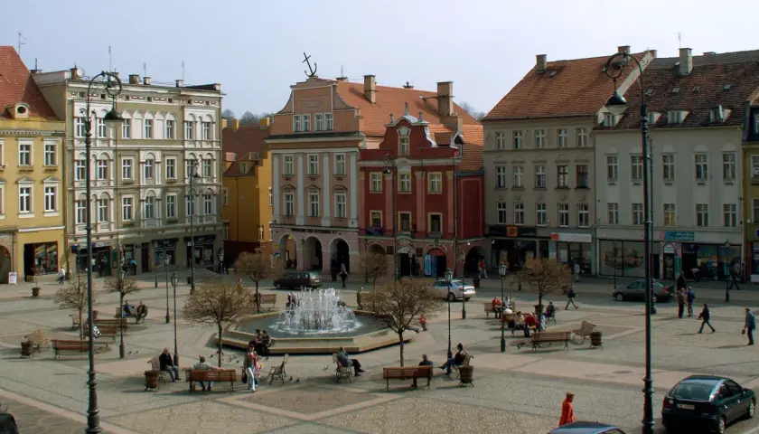Rynek Wałbrzych tętni życiem. Ludzie odpoczywają przy fontannie, spacerują między kamienicami.