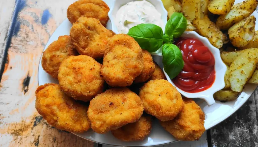 Chrupiące nuggetsy z kurczaka, złociste frytki i sosy: ketchup i majonez. Idealna przekąska na każdą okazję.