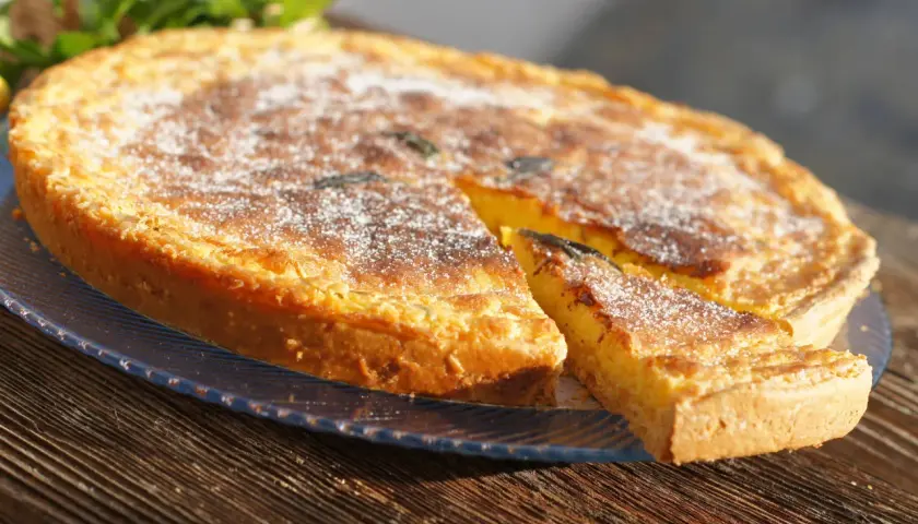 Tarta dorada con azúcar glas, un trozo cortado, como un flao ibiza.