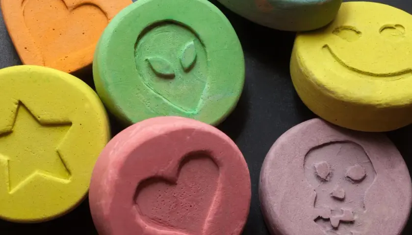 Kolorowe tabletki z symbolami: serce, gwiazda, uśmiech, kosmita, czaszka. Niektóre mogą zawierać mdma.