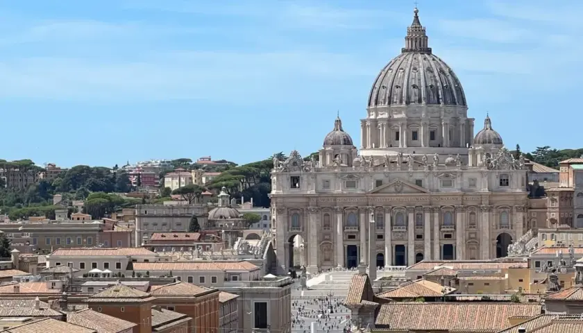 Vista panoramica di Roma con la Basilica di San Pietro in primo piano. Si intravedono i tetti della città e il cielo azzurro. Vicino alla stazione Ottaviano, un luogo iconico.