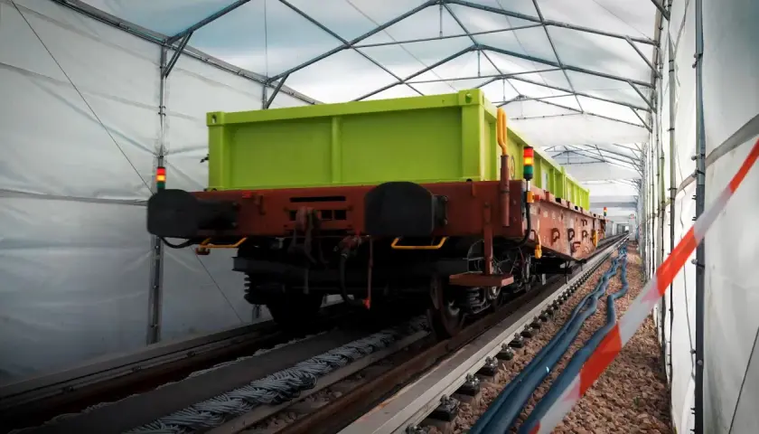 Zielony wagon towarowy na torach pod namiotem. Może to być pierwsza kolej na świecie w takim wydaniu.