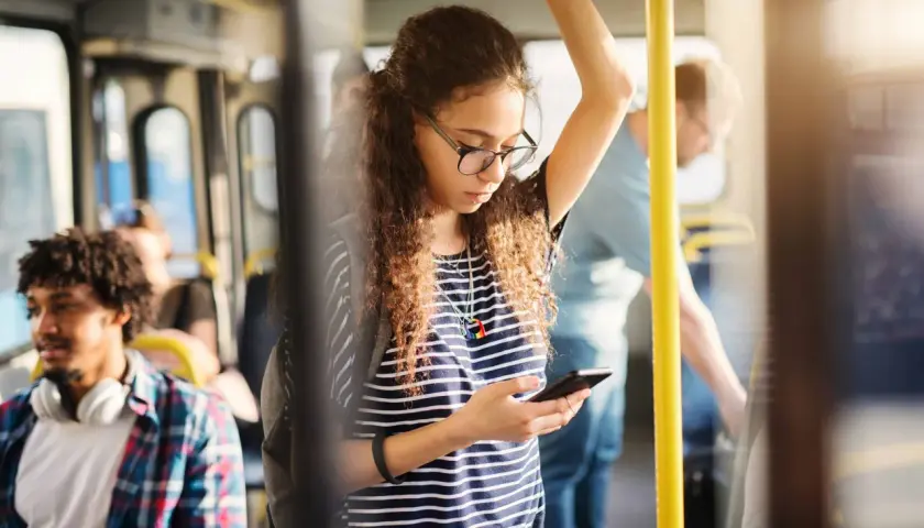 Ragazza sul bus guarda il suo telefono, forse controllando l'orario della metro linea A di Roma per il suo prossimo viaggio.