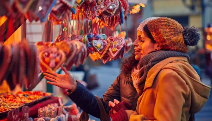 Dos mujeres admiran dulces y galletas en forma de corazón en un mercadillo de Santillana del Mar.