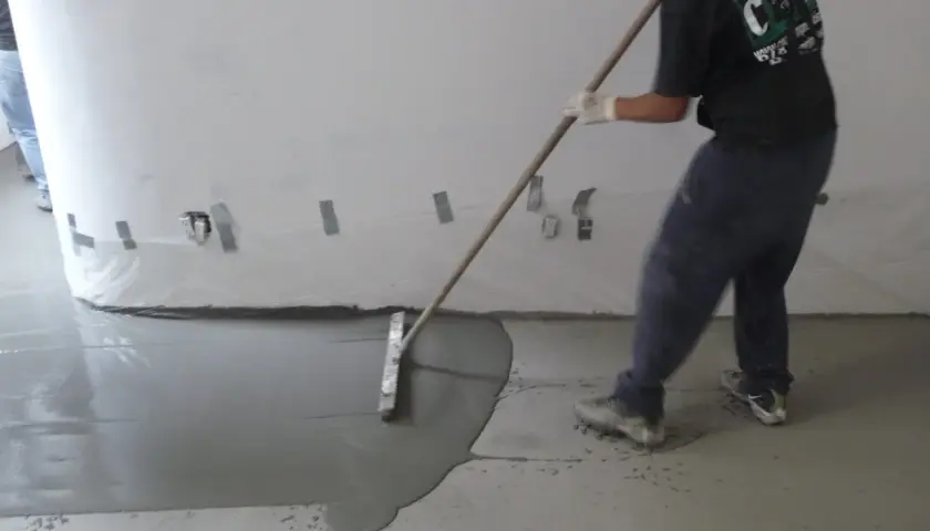 Man behandla betonggolv inomhus med en bredspackel för att jämna ut det flytande materialet.