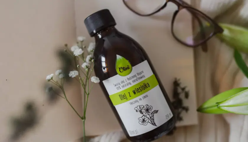 Butelka z naturalnym olejem z wiesiołka, idealnym do pielęgnacji włosów. Delikatne kwiaty podkreślają jego naturalne pochodzenie.