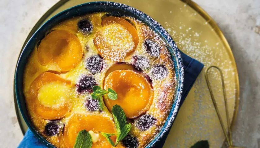 Un délicieux clafoutis abricot, saupoudré de sucre glace et garni de feuilles de menthe fraîche.