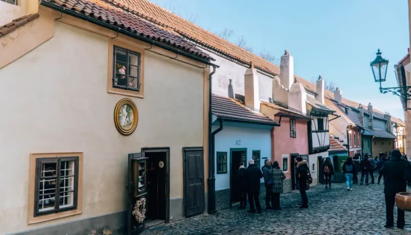 Uliczka Złota w Pradze, z kolorowymi domkami i brukowaną ścieżką, przyciąga turystów.