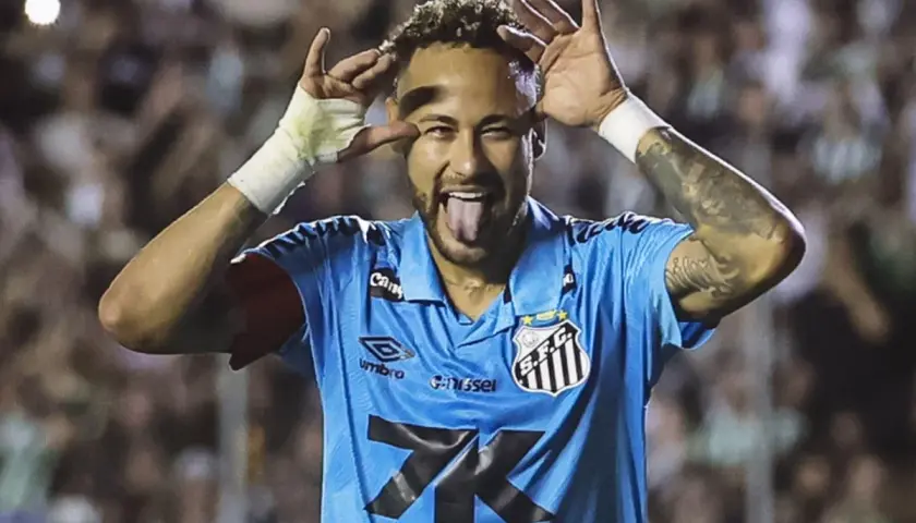 Neymar, w niebieskiej koszulce Santos, z językiem na wierzchu i rękami przy oczach, świętuje bramkę. Czy to zapowiedź jego kolejnego transferu?