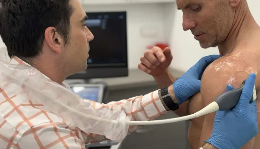 Lekarz wykonuje USG barku pacjenta, diagnozując entezopatię barku.