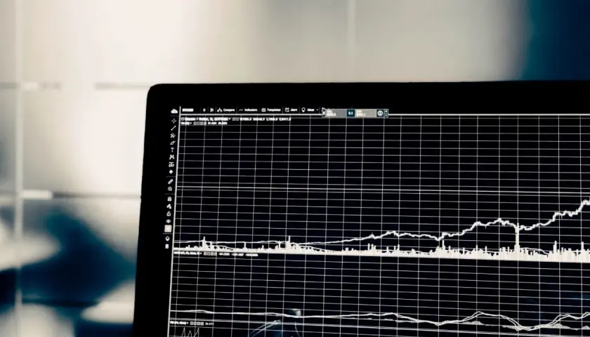 Wykresy na ekranie laptopa pokazują zmienność cen akcji. Analiza tych danych pomaga w ocenie, co to jest scoring finansowy i jak podejmować trafne decyzje inwestycyjne.