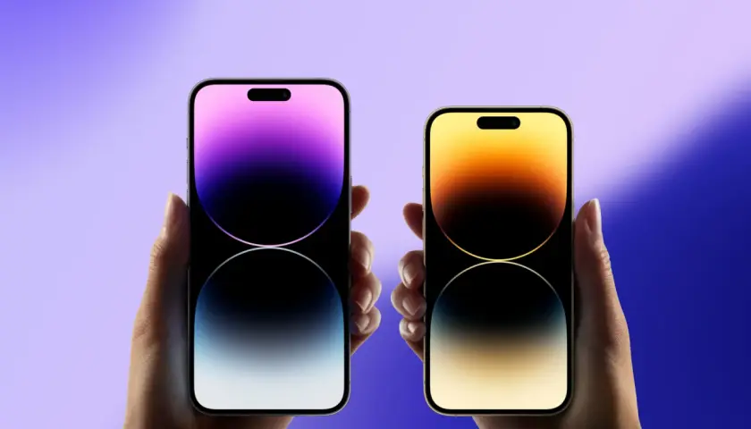 Dwie dłonie trzymają iPhone'y, gdy wyszedł iPhone 15. Jeden z fioletowym gradientem, drugi z żółto-pomarańczowym.