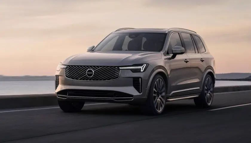 Szary Volvo XC90 jedzie po drodze nad morzem. Sprawdź aktualną volvo xc90 cena.