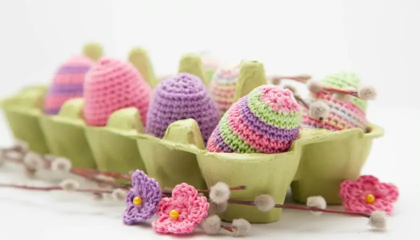 Uova di Pasqua all'uncinetto in un portauova verde, perfette per idee lavoretti con la lana facili e colorati.