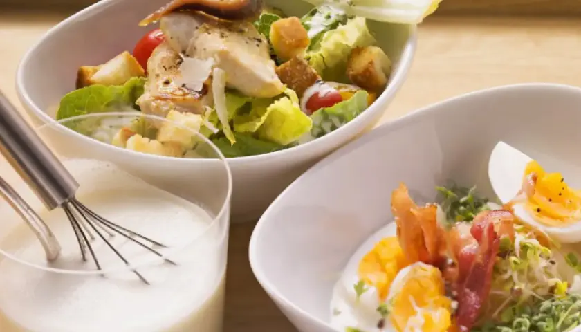 Ensalada César con pollo y huevo duro, acompañada de una cremosa salsa césar vegana.