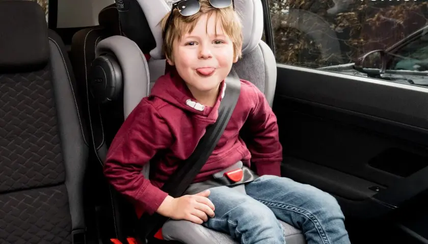 Chłopiec w foteliku samochodowym Britax Römer, z językiem na wierzchu, w okularach przeciwsłonecznych na głowie. Jaki fotelik samochodowy wybrać?
