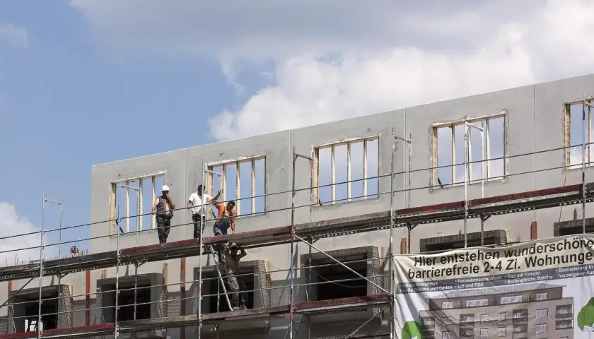 Chantiers de construction : des ouvriers sur des échafaudages travaillent sur un immeuble en cours de construction, projet de crédit immobilier avec travaux.