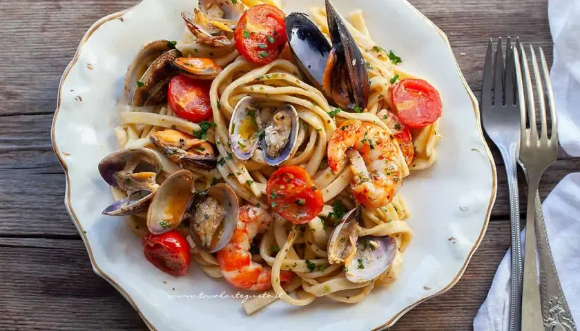 Un piatto invitante di scialatielli ai frutti di mare, con cozze, vongole, gamberi e pomodorini freschi, guarnito con prezzemolo.