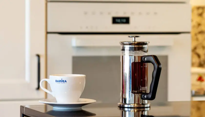 Świeżo zaparzona kawa w french pressie i filiżanka z logo Darvea. Idealna ilość kawy do french pressa czeka na degustację.
