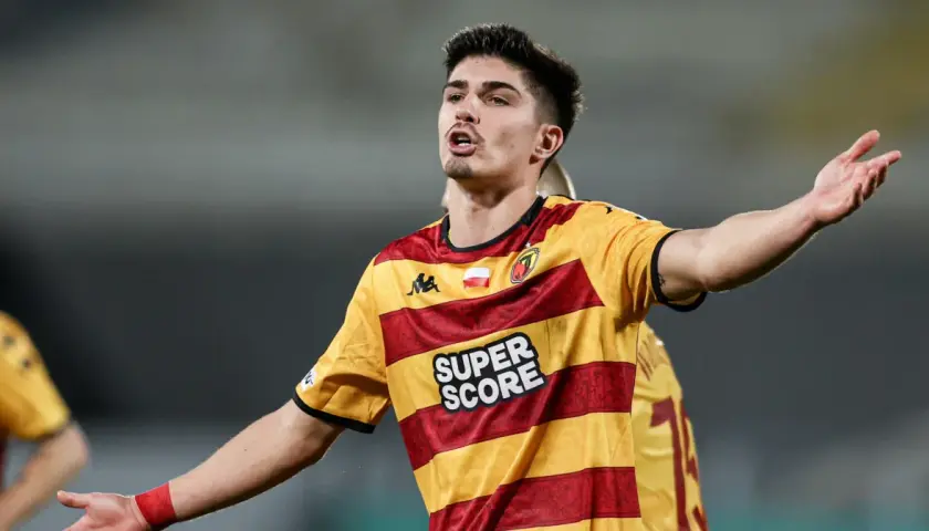 Piłkarz Korony Kielce w żółto-czerwonej koszulce z napisem "SUPER SCORE" gestykuluje podczas meczu z Jagiellonią Białystok.