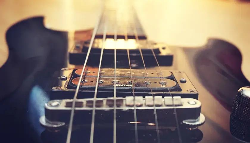 Zbliżenie na czarną gitarę elektryczną, jej struny i przetworniki. Czy to brzmienie mainstream co to?