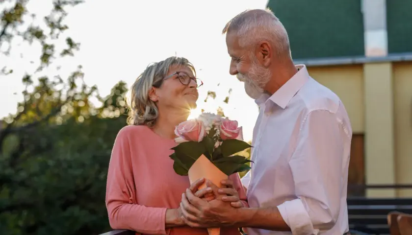 Para świętuje 17 rocznicę ślubu. Mężczyzna wręcza kobiecie bukiet róż, patrzą na siebie z miłością.
