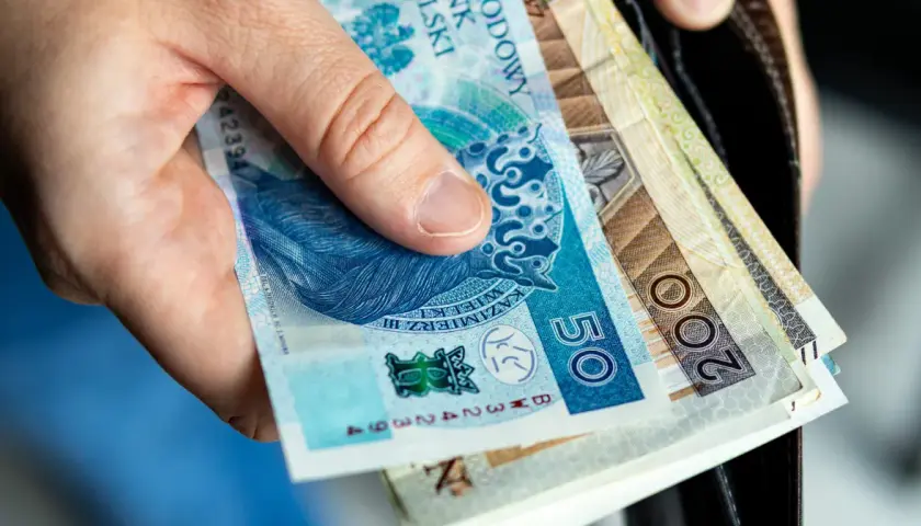 Dłoń trzyma polskie banknoty: 50 zł i 200 zł. Wkrótce trzeba będzie zapłacić czynsz.