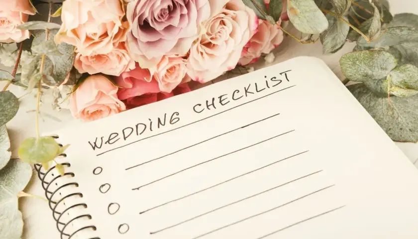 Bukiet róż i eukaliptusa obok notatnika z napisem "Wedding Checklist". Idealny punkt, od czego zacząć planowanie wesela.
