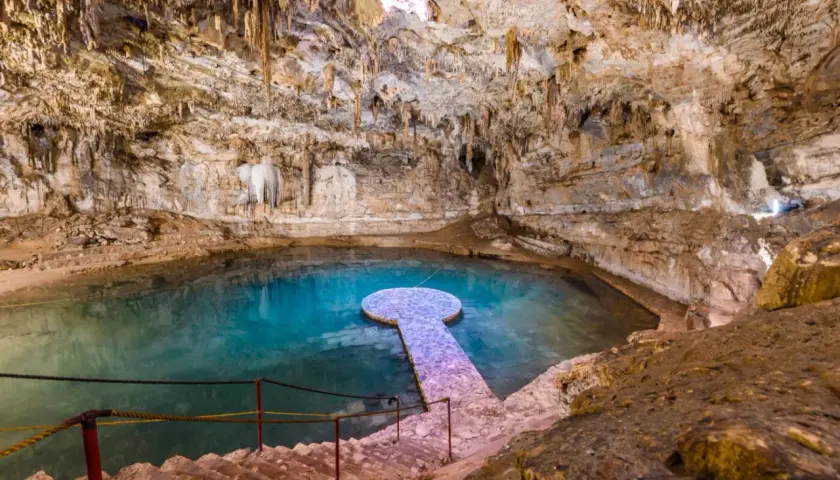 Ein atemberaubender Cenote in Mexiko mit kristallklarem, türkisfarbenem Wasser, Stalaktiten und einer steinernen Plattform.