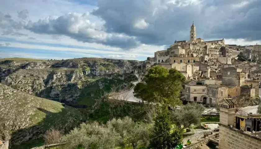 Ancient cave dwellings and a bell tower rise from a hillside in Matera, Italy. Explore this historic city for unique things to do.