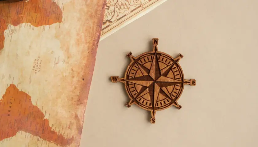 Rosa de los vientos de madera, símbolo de guía y el rosa de los vientos significado espiritual. Un mapa antiguo y una brújula de madera.